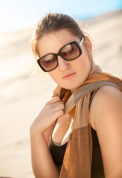Closeup portrait of brunette woman in sunglasses and scarf at desert
