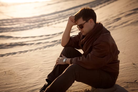 Portrait of handsome man sitting and thinking on sand dune