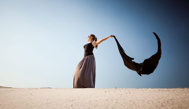 Photo of arabian woman with long cloth at desert on windy day