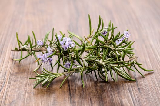 Rosemary with violet flowers on a wooden board