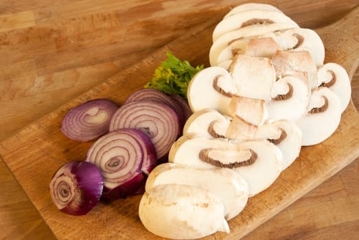 Chopped fresh raw onion and mushroom on a wooden board