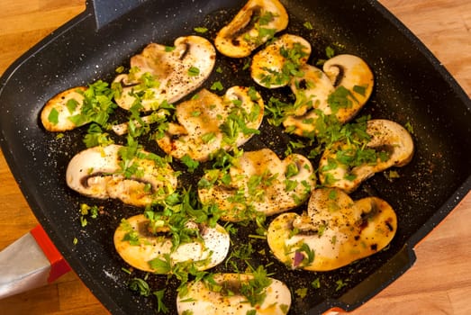 Cooked field mushrooms in pan with olive oil, parsley and spices