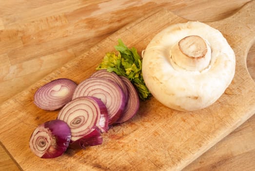 Chopped fresh raw onion and mushroom on a wooden board