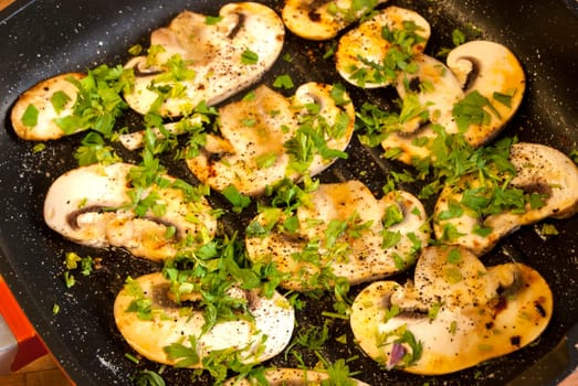 Cooked field mushrooms in pan with olive oil, parsley and spices