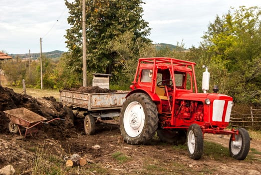Vintage red grunge tractor on rural landscape