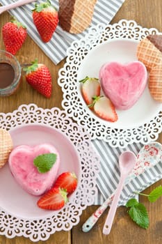 Ice cream in heart shape with fresh strawberries on pink plates