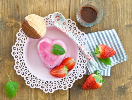 Ice cream in heart shape with fresh strawberries on pink plates