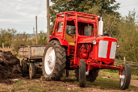 Vintage red grunge tractor on rural landscape