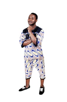 A handsome young black man in a colorful African clothing with his.hand on his shin, isolated for white background..