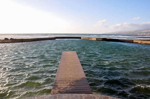 Empty Wooden Pier With Sea And Cloudy Sky On Background