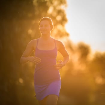 Young woman running outdoors on a lovely sunny summer evening (shallow DOF  color toned image)