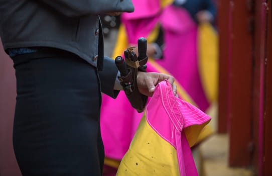 The bullfighter prepares his daggers behind the barrier of the bullring