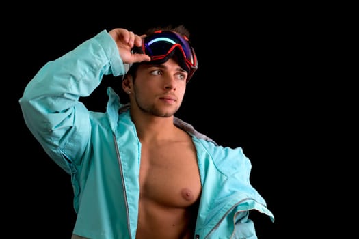Muscular skier or snowboarder with open jacket on naked muscular torso, isolated on black