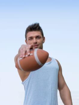 Muscular american football with ball in hand, pointing finger to camera