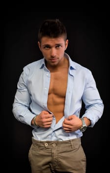 Confident, attractive young man with open shirt on muscular torso, ripped abs and pecs