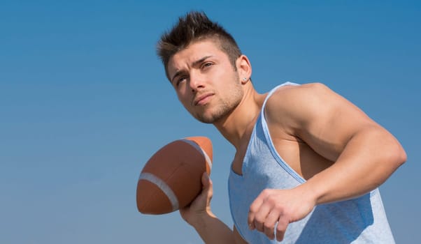 Muscular american football player ready to throw ball in hand. Outdoors shot