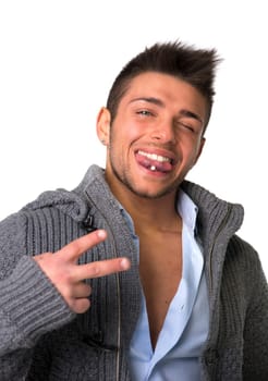 Attractive young man smiling with tongue piercing, doing victory sign with two fingers