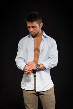 Confident, attractive young man with open shirt on muscular torso, ripped abs and pecs