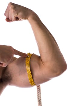 Muscular shirtless young man measuring arm (bicep and tricep) with tape measure, close-up of arm on white background