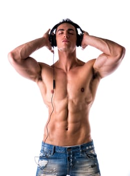 Muscular man shirtless, standing, listening to music on headphones, with eyes closed