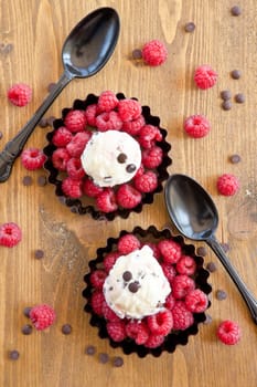 Ice cream with raspberries and chocolate on rustic wood