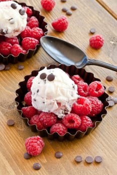 Ice cream with raspberries and chocolate on rustic wood