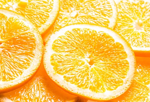 Full frame background of juicy orange slices showing the texture of the pulp, pith and rind with an angled perspective