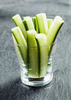 Delicious succulent cucumber crudties cut into thin strips or batons and served in a glass container on a buffet as appetizers to dip in a savory sauce