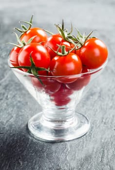Fresh ripe red juicy cherry tomatoes with stalks served in a conical glass container as crudites to dip in a savory sauce