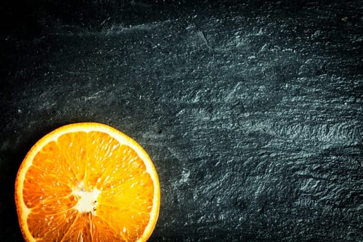 Sliced halved fresh ripe orange on a dark texture background with copyspace