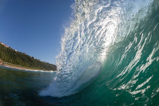 Ocean wave crashing water power energy on shallow reefs nearby beach coastline