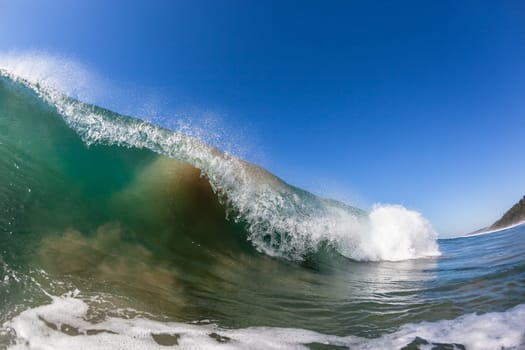 Ocean wave crashing water power energy on shallow reefs nearby beach coastline