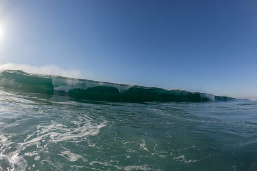 Ocean wave crashing water power energy on shallow reefs nearby beach coastline