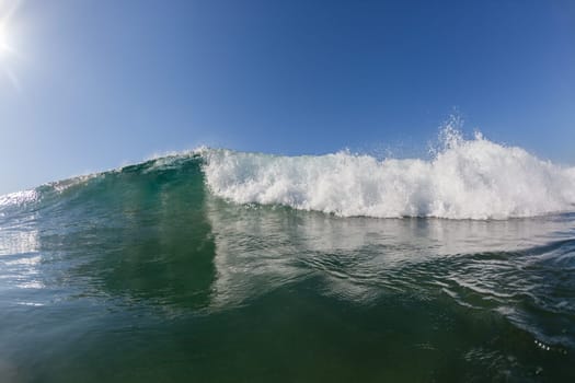 Ocean wave crashing white water power energy on shallow reefs nearby beach coastline