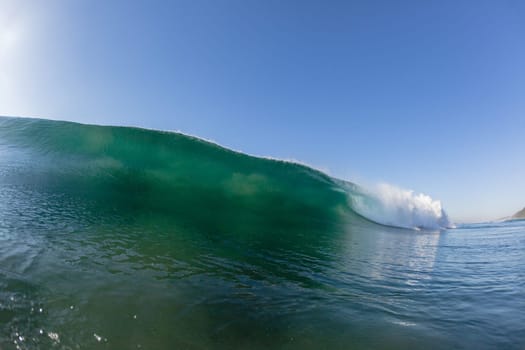 Ocean wave crashing water power energy on shallow reefs nearby beach coastline