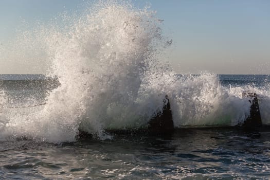Ocean wave crashing white water spray against tidal pool coastline