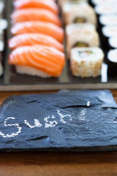 Closeup of healthy freshly prepared sushi rolls with decorative label stone with text in chalk