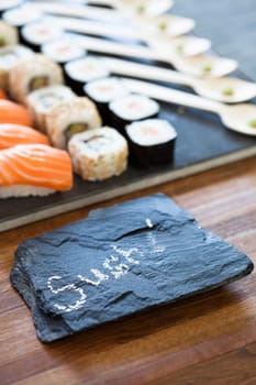 Closeup of healthy freshly prepared sushi rolls with decorative label stone with text in chalk