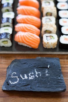 Closeup of healthy freshly prepared sushi rolls with decorative label stone with text in chalk