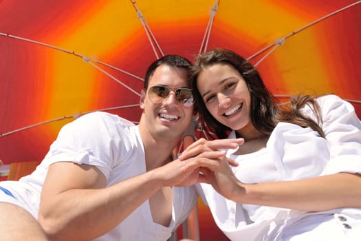 happy young couple have fun and relax  on the summer with heart drawing on beach sand