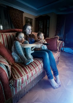 Young mother with two daughters watching horror movie at night