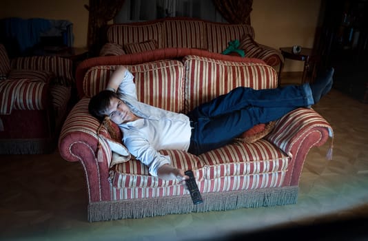 Portrait of man switching TV channels on sofa at night