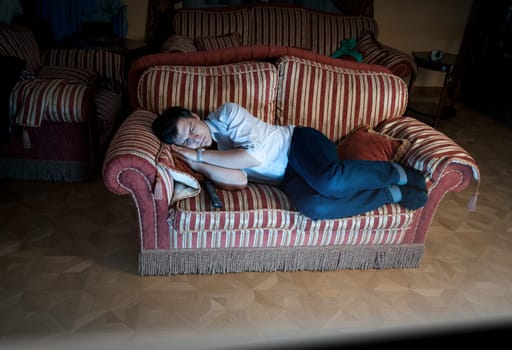 Portrait of man sleeping on sofa at night near TV