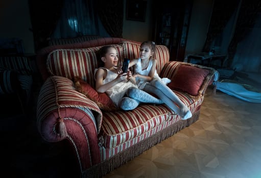 Photo of two girls fighting for TV remote on sofa at night