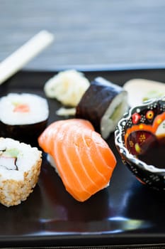 Closeup of plate of healthy freshly prepared sushi with bowl soy sauce