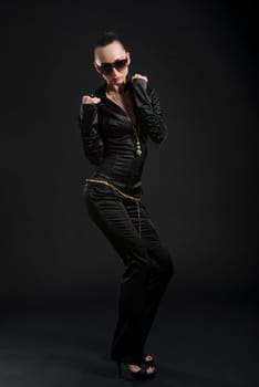 Full length shot of beautiful Caucasian woman wearing black bodysuit and dancing, against black background