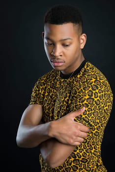 Portrait of handsome dark skinned male model wearing panther pattern t-shirt against black background