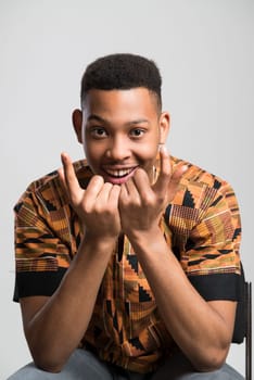 Portrait of handsome dark skinned male model smiling and wearing traditionally African clothes against white background