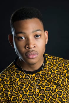 Portrait of handsome dark skinned male model wearing panther pattern t-shirt against black background