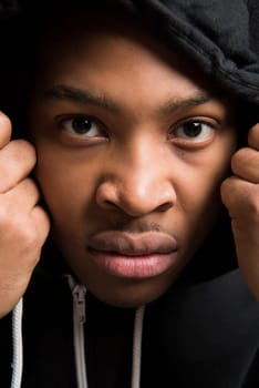 Portrait of handsome dark skinned male model wearing black hooded jumper